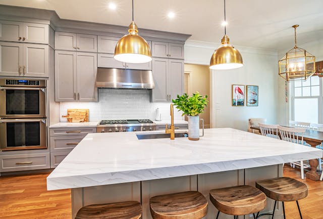 Renovated kitchen with white marble island and gold pendant lights